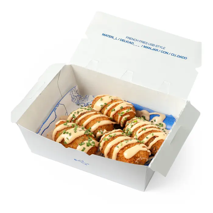 Croquetas de guiso de ternera con salsa por encima, en su caja blanca